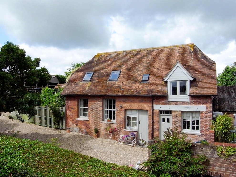 This is an example of a country two-storey brick exterior in Dorset with a clipped gable roof.