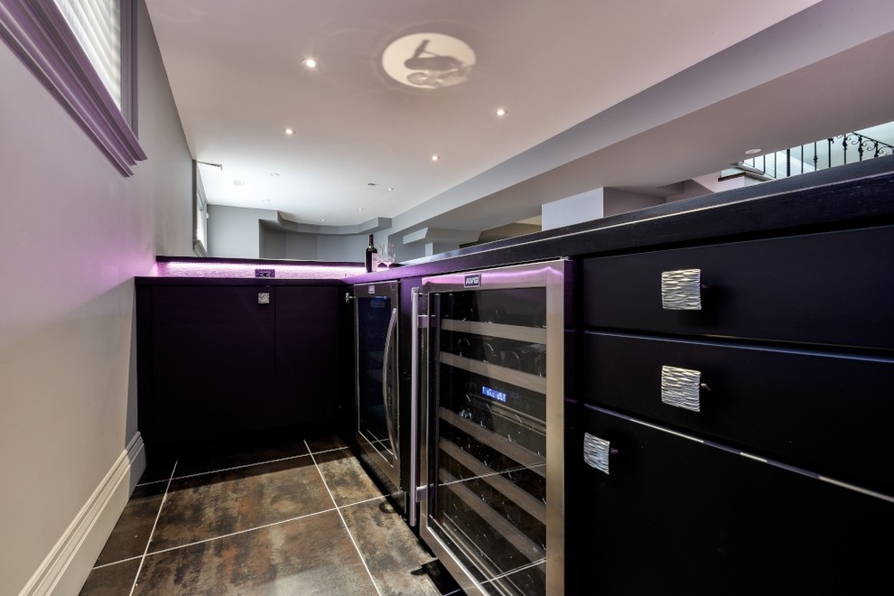 This is an example of a large modern l-shaped wet bar in Toronto with flat-panel cabinets, black cabinets, wood benchtops, porcelain floors and black floor.