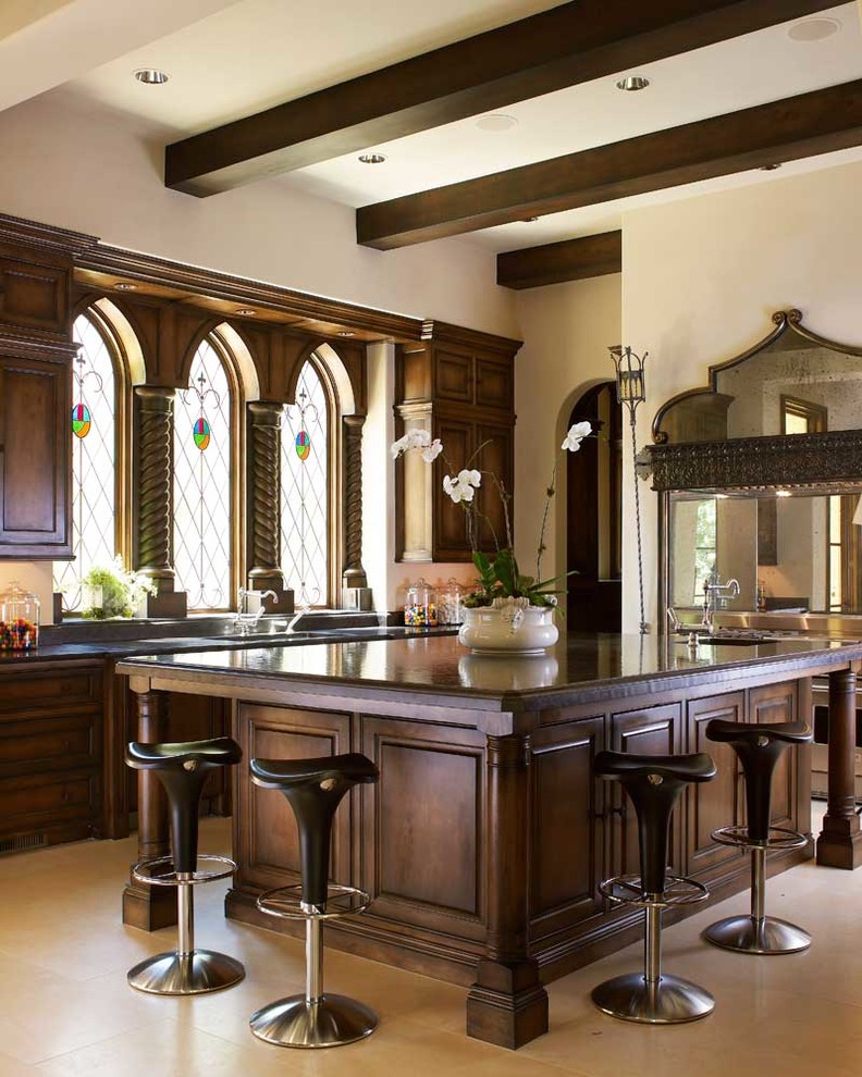 Mediterranean kitchen in Dallas with dark wood cabinets, with island, beige floor and brown benchtop.