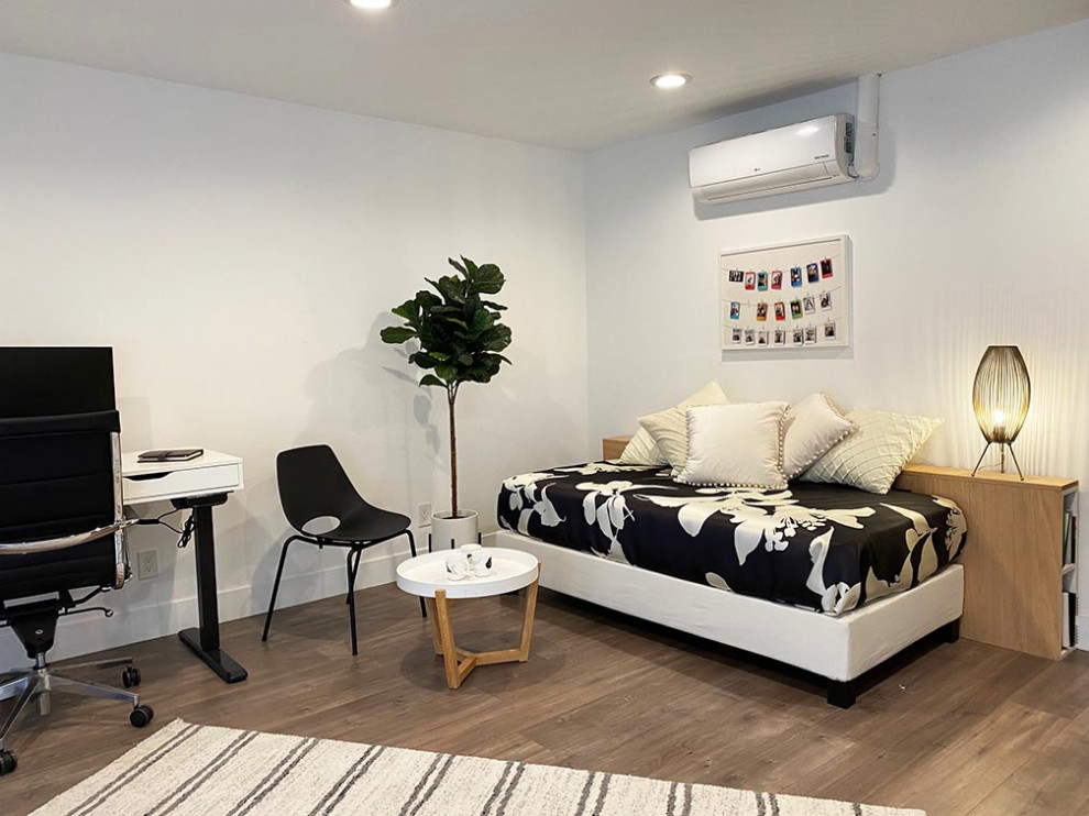 Modern inredning av ett litet arbetsrum, med vita väggar, mellanmörkt trägolv, ett fristående skrivbord och grått golv