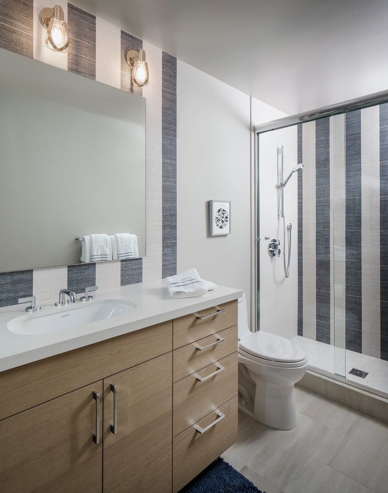 This is an example of a transitional 3/4 bathroom in San Diego with flat-panel cabinets, beige cabinets, an alcove shower, multi-coloured tile, white walls, an undermount sink, beige floor, a sliding shower screen and white benchtops.