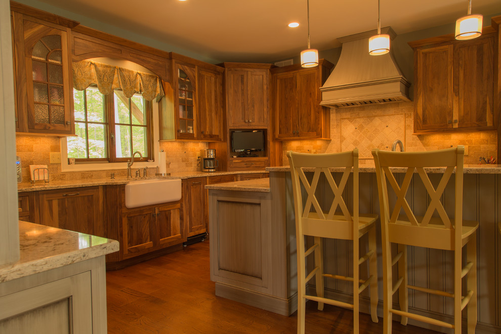This is an example of a mid-sized traditional u-shaped open plan kitchen in New York with a farmhouse sink, beaded inset cabinets, medium wood cabinets, granite benchtops, beige splashback, stone tile splashback, stainless steel appliances, medium hardwood floors and with island.
