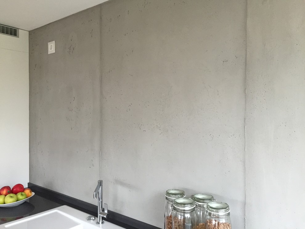 Offene, Einzeilige, Große Moderne Küche ohne Insel mit Einbauwaschbecken, flächenbündigen Schrankfronten, weißen Schränken, Granit-Arbeitsplatte, Küchenrückwand in Grau, Rückwand aus Zementfliesen, Küchengeräten aus Edelstahl, gebeiztem Holzboden und braunem Boden in Köln