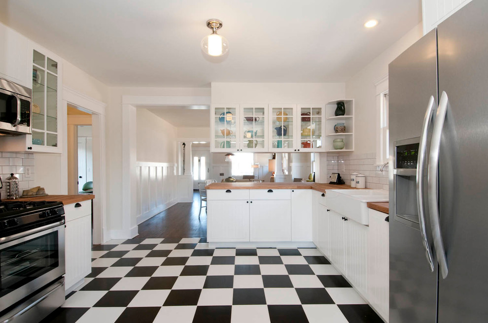 Mid-sized arts and crafts u-shaped eat-in kitchen in Los Angeles with a peninsula, beaded inset cabinets, white cabinets, wood benchtops, white splashback, subway tile splashback, stainless steel appliances, a farmhouse sink and ceramic floors.