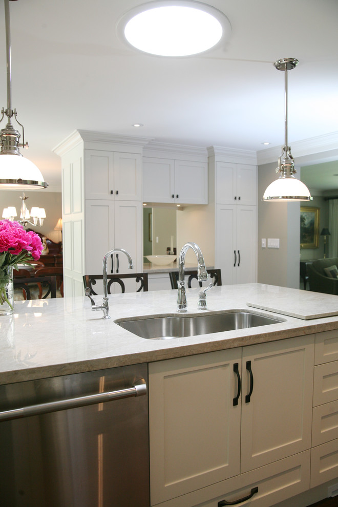 Large transitional l-shaped dark wood floor and brown floor eat-in kitchen photo in Toronto with an undermount sink, shaker cabinets, white cabinets, stainless steel appliances and an island