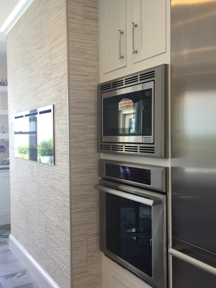 Example of a large transitional ceramic tile and multicolored floor kitchen design with a farmhouse sink, beaded inset cabinets, white cabinets, quartz countertops, metallic backsplash, ceramic backsplash, stainless steel appliances and an island