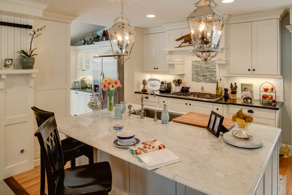 Photo of a traditional galley eat-in kitchen in Detroit with an undermount sink, shaker cabinets, white cabinets, granite benchtops, white splashback, glass tile splashback and stainless steel appliances.