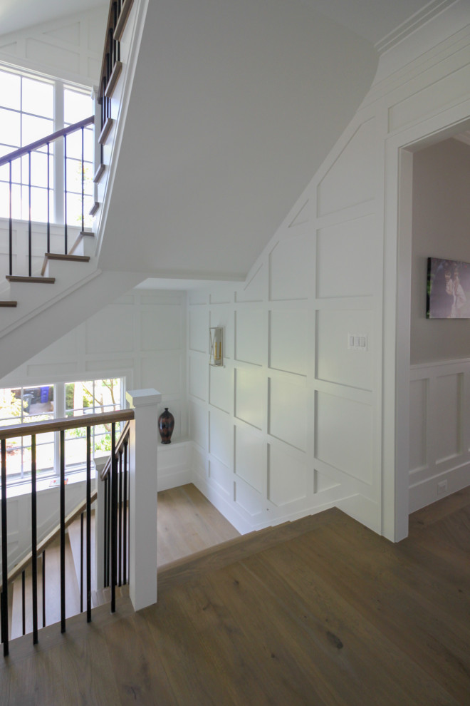 Design ideas for a large classic wood u-shaped wood railing staircase in DC Metro with wood risers and wainscoting.