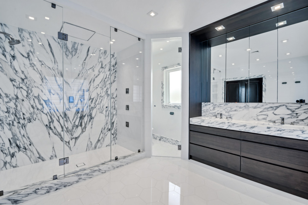 Photo of an expansive traditional master bathroom in New York with flat-panel cabinets, brown cabinets, a drop-in tub, an open shower, a bidet, white tile, marble, white walls, marble floors, a drop-in sink, marble benchtops, white floor, a hinged shower door, white benchtops, an enclosed toilet, a double vanity, a built-in vanity and coffered.