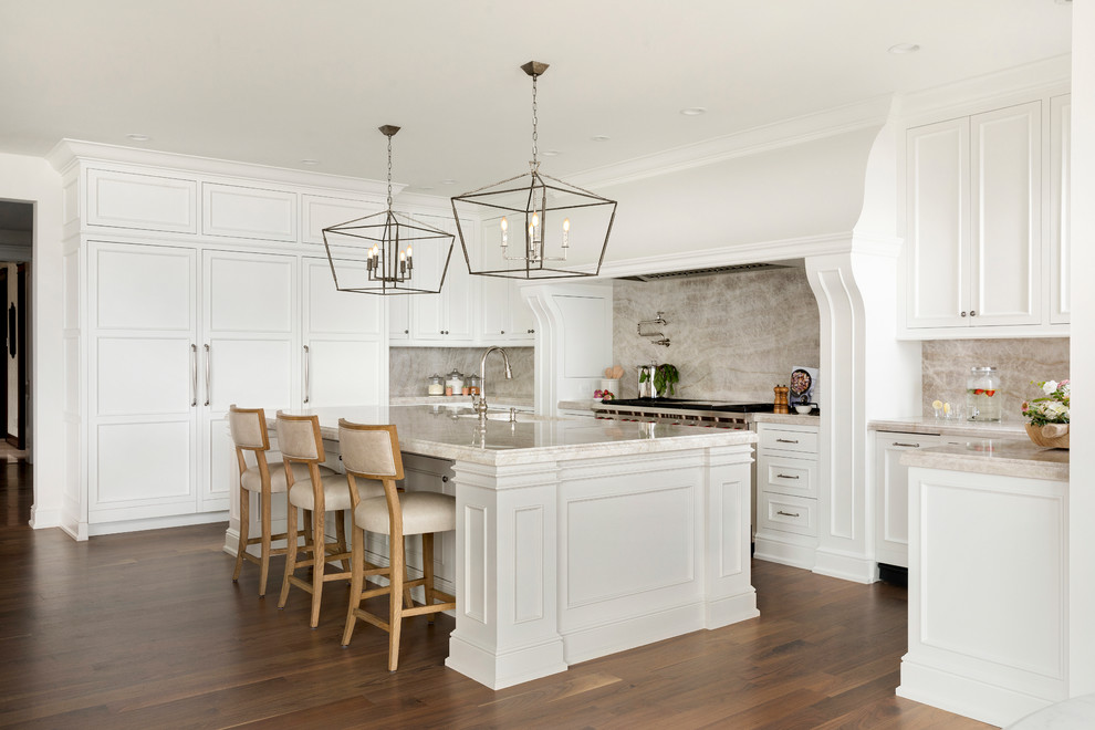Design ideas for a traditional u-shaped kitchen in Minneapolis with an undermount sink, recessed-panel cabinets, white cabinets, beige splashback, stone slab splashback, panelled appliances, medium hardwood floors, with island, brown floor and beige benchtop.