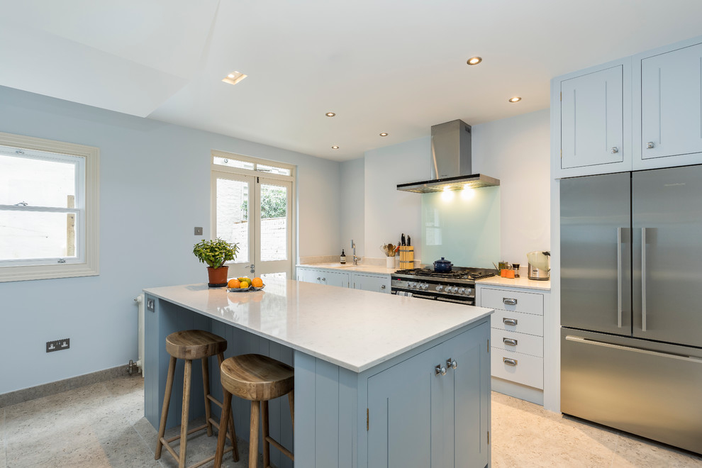 Design ideas for a mid-sized transitional single-wall open plan kitchen in London with flat-panel cabinets, blue cabinets, stainless steel appliances and with island.