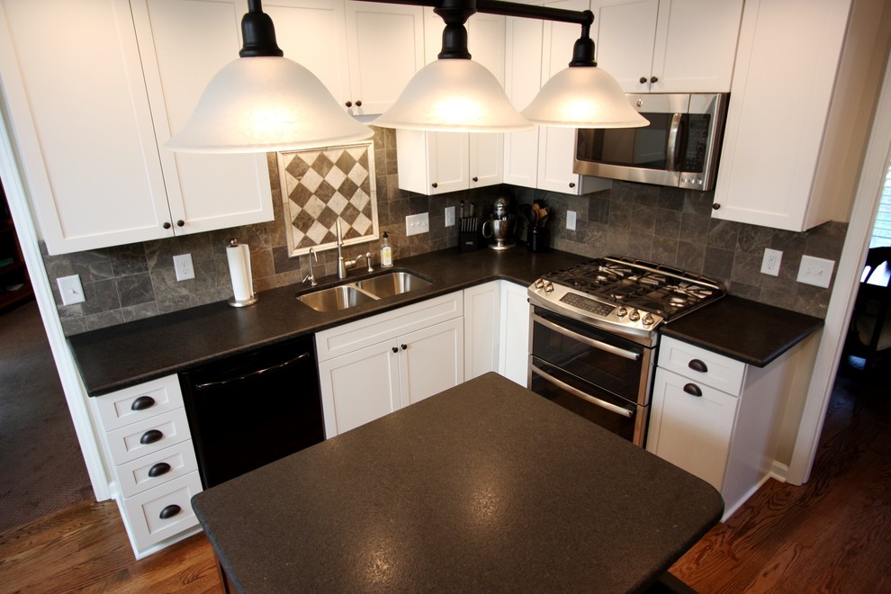 Example of a mid-sized transitional l-shaped medium tone wood floor eat-in kitchen design in Raleigh with an undermount sink, shaker cabinets, white cabinets, granite countertops, gray backsplash, stone tile backsplash, stainless steel appliances and an island