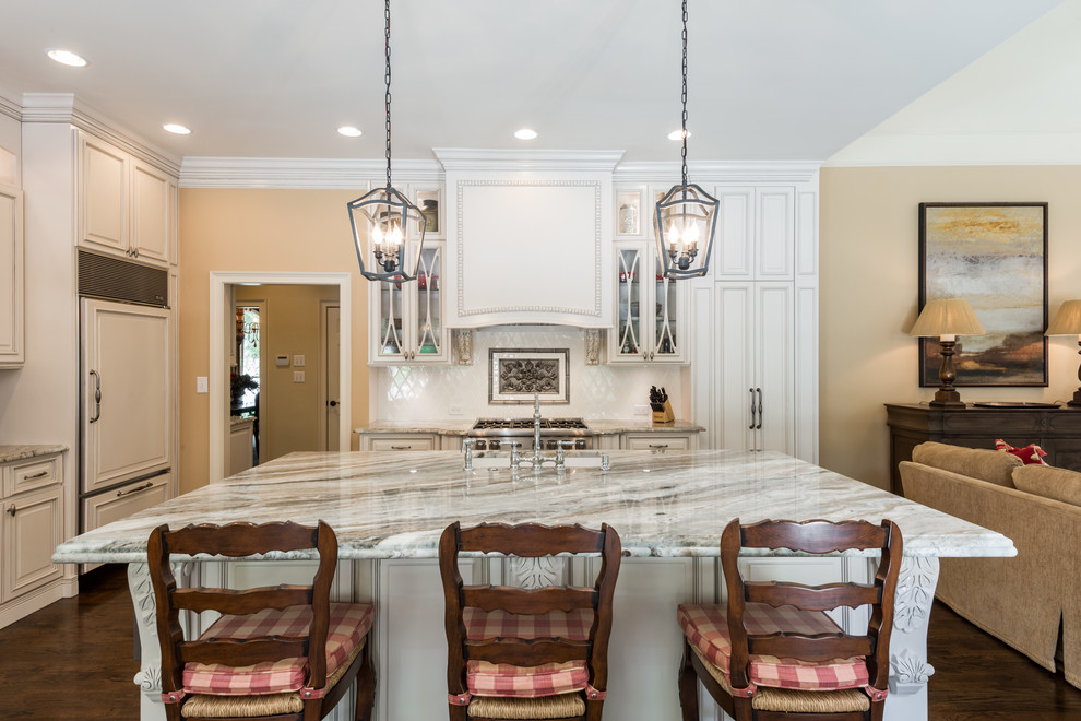 This is an example of a traditional l-shaped kitchen in Atlanta with shaker cabinets, white cabinets, white splashback, stainless steel appliances, dark hardwood floors, with island and brown floor.