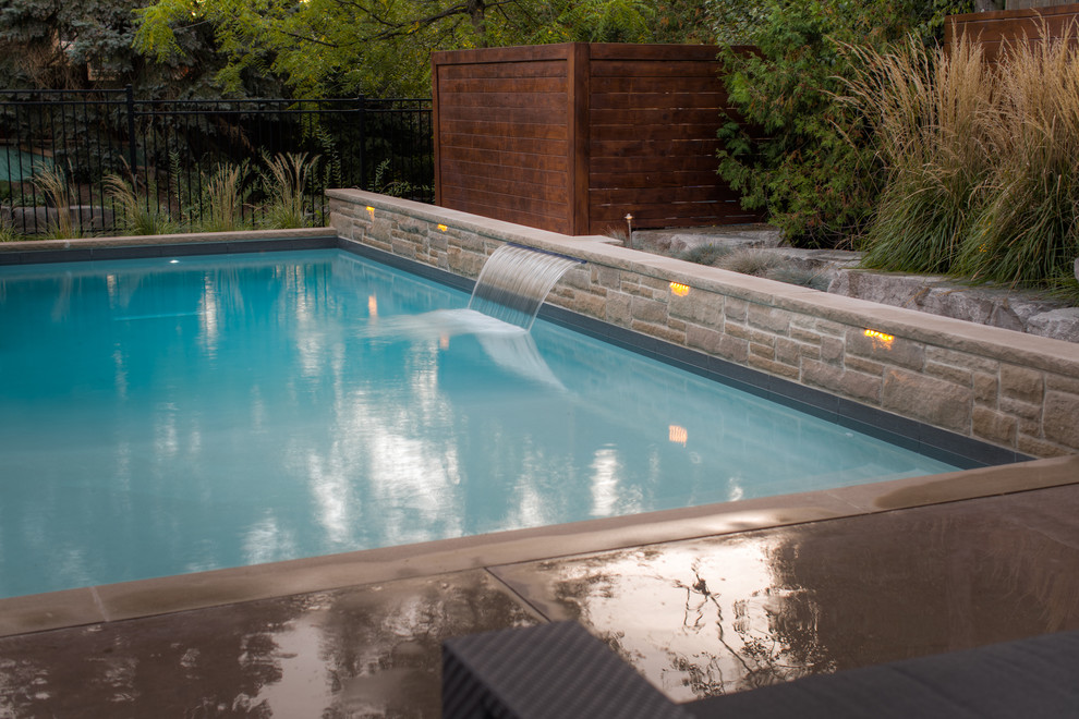 Large transitional backyard rectangular pool in Toronto with a hot tub and concrete slab.