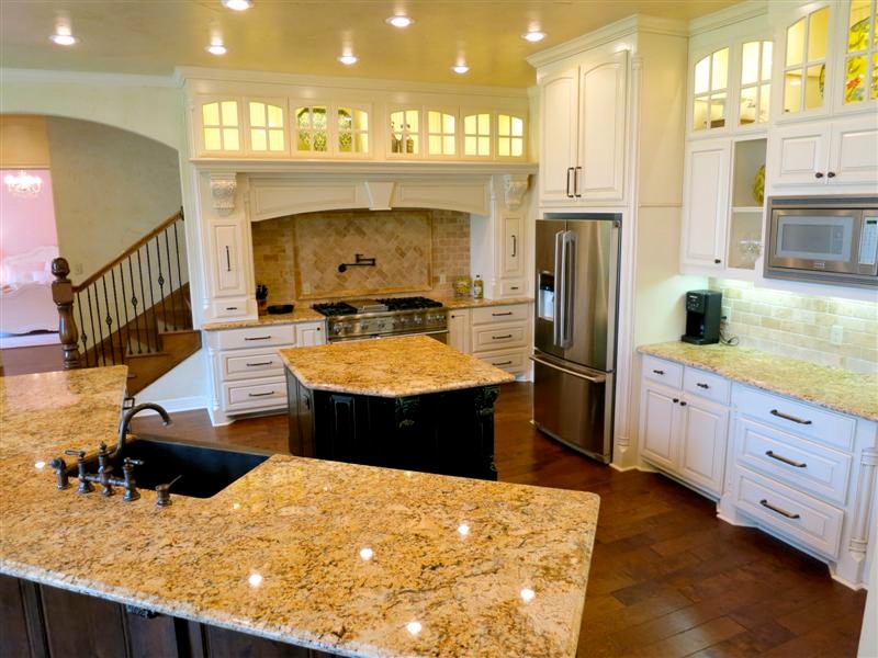 Inspiration for a large mediterranean l-shaped eat-in kitchen in Houston with a double-bowl sink, raised-panel cabinets, white cabinets, granite benchtops, beige splashback, stone tile splashback, stainless steel appliances, dark hardwood floors and with island.