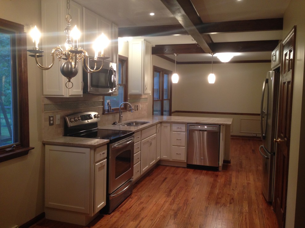 Inspiration for a mid-sized transitional l-shaped medium tone wood floor kitchen remodel in Cincinnati with a double-bowl sink, raised-panel cabinets, white cabinets, granite countertops, beige backsplash, ceramic backsplash and stainless steel appliances