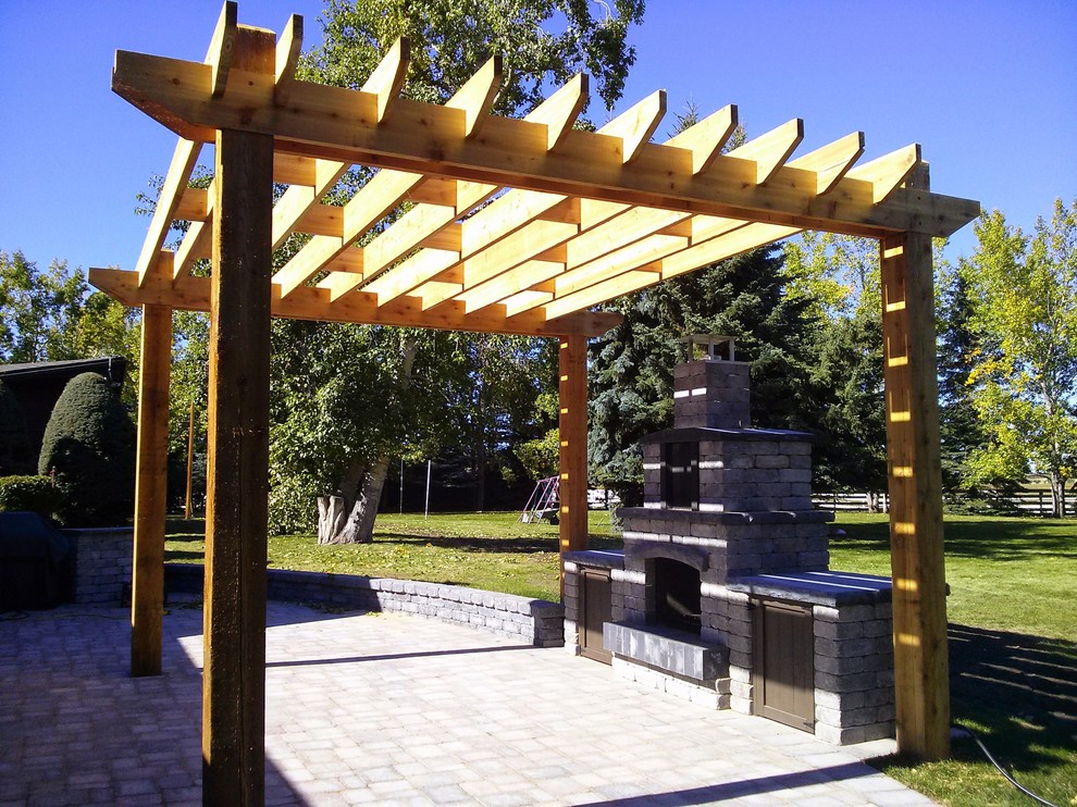 Design ideas for a mid-sized traditional backyard patio in Calgary with a pergola and brick pavers.