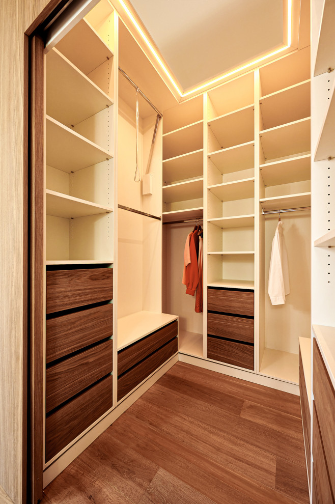 Medium sized modern gender neutral dressing room in Stuttgart with louvered cabinets, medium wood cabinets, medium hardwood flooring and brown floors.