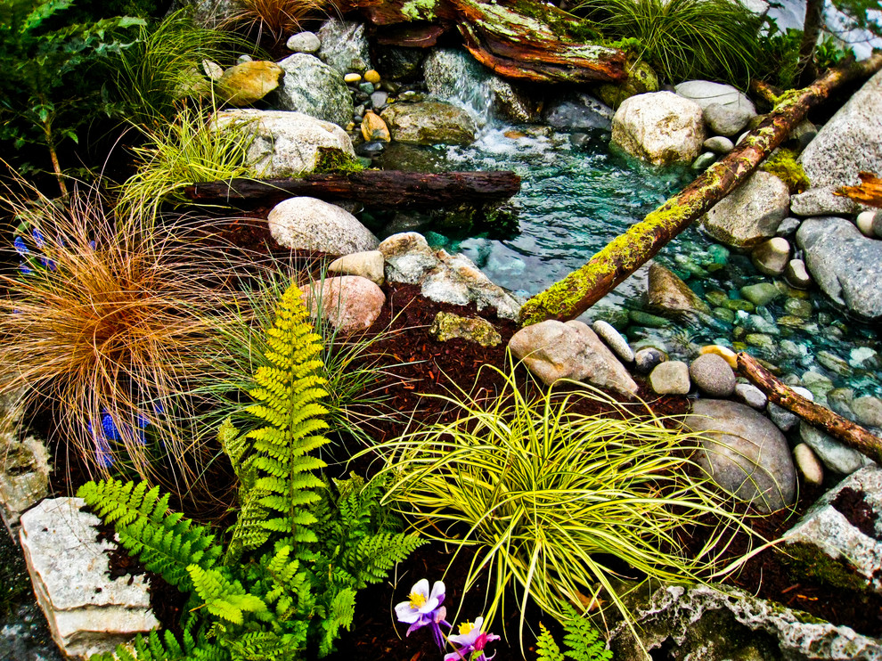 This is an example of a mid-sized rustic full sun backyard stone water fountain landscape in Seattle for spring.