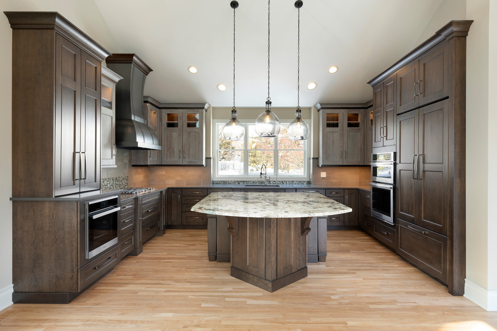 Mid-sized transitional u-shaped kitchen in Minneapolis with recessed-panel cabinets, dark wood cabinets, quartz benchtops, grey splashback, ceramic splashback, stainless steel appliances, with island, a single-bowl sink, light hardwood floors, beige floor and grey benchtop.
