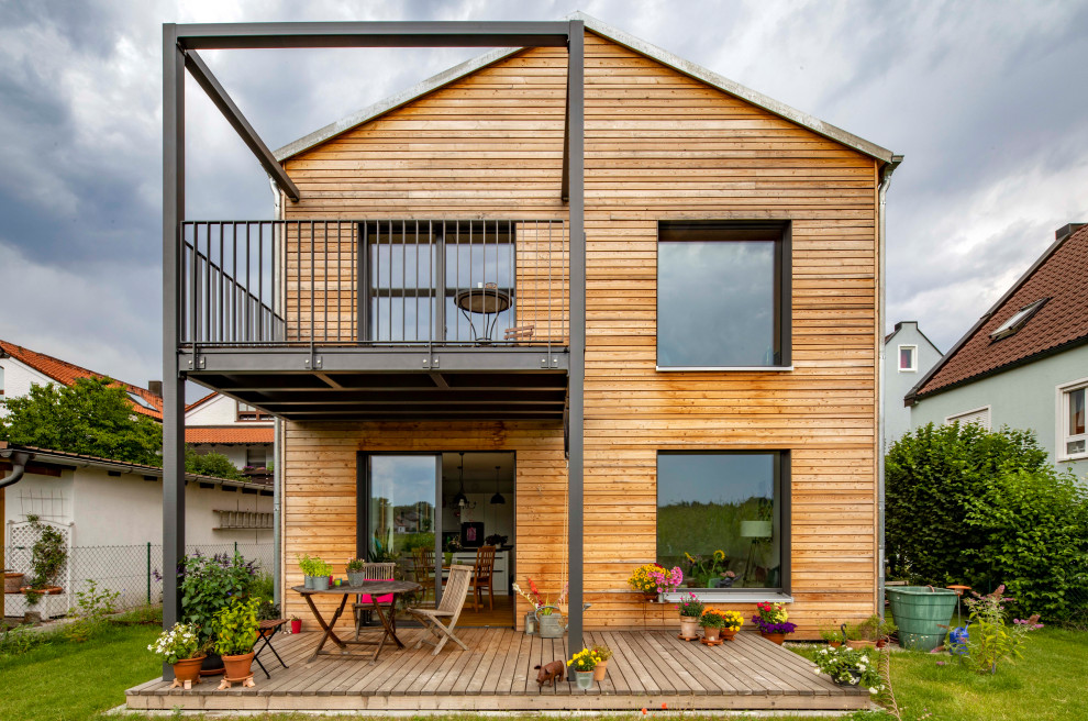 Imagen de fachada de casa gris escandinava de dos plantas con revestimiento de madera, tejado a dos aguas, tejado de teja de barro y tablilla