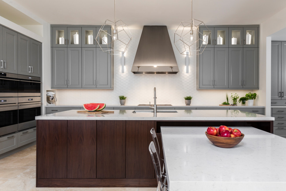 Large traditional u-shaped kitchen/diner in Houston with a single-bowl sink, recessed-panel cabinets, grey cabinets, engineered stone countertops, white splashback, ceramic splashback, integrated appliances, travertine flooring, an island, beige floors and white worktops.