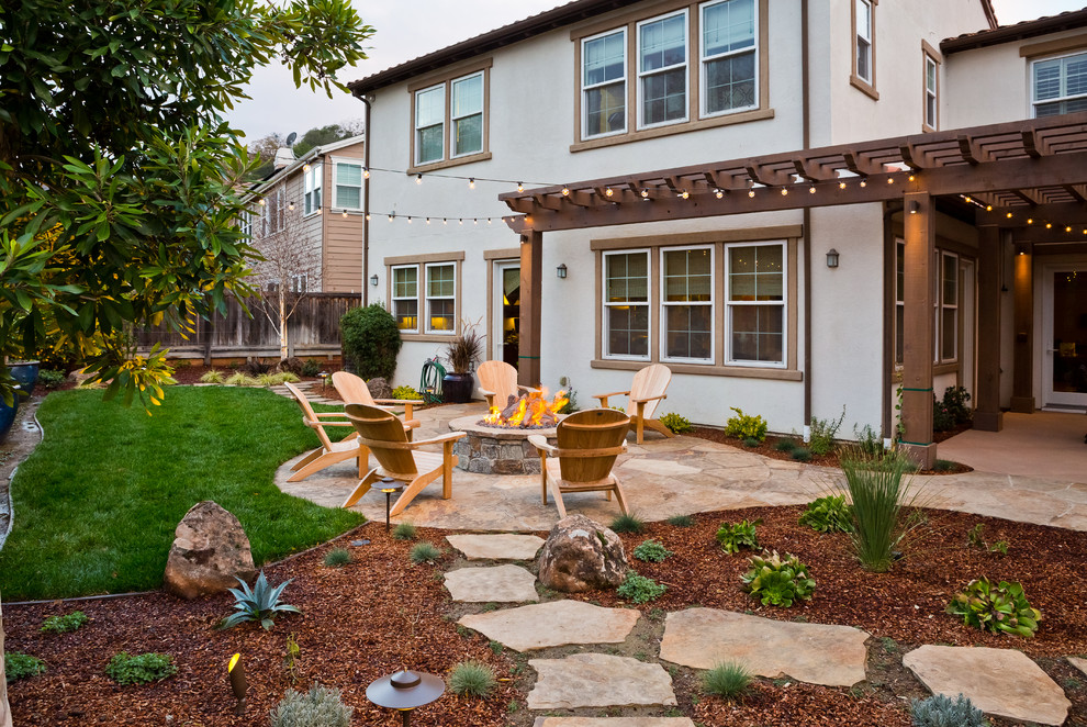 This is an example of a mid-sized country backyard full sun garden in San Francisco with a fire feature and natural stone pavers.