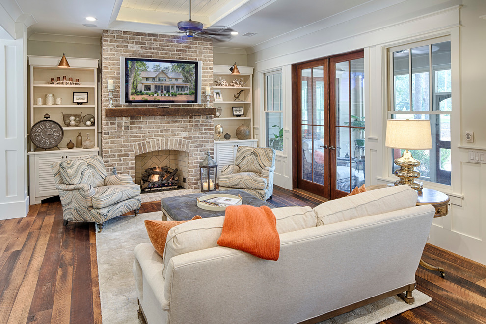 Inspiration for a mid-sized country open concept living room in Grand Rapids with white walls, dark hardwood floors, a standard fireplace, a brick fireplace surround and a wall-mounted tv.