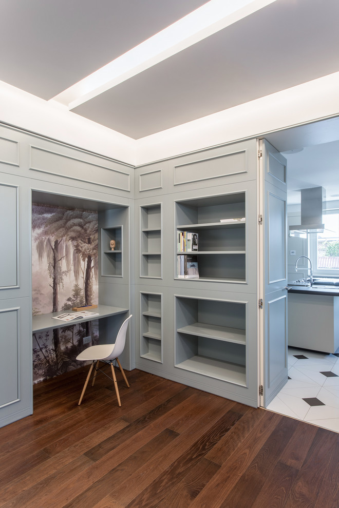 Photo of an expansive traditional home office in Milan with a library, white walls, medium hardwood floors, a standard fireplace, a stone fireplace surround, a built-in desk and brown floor.