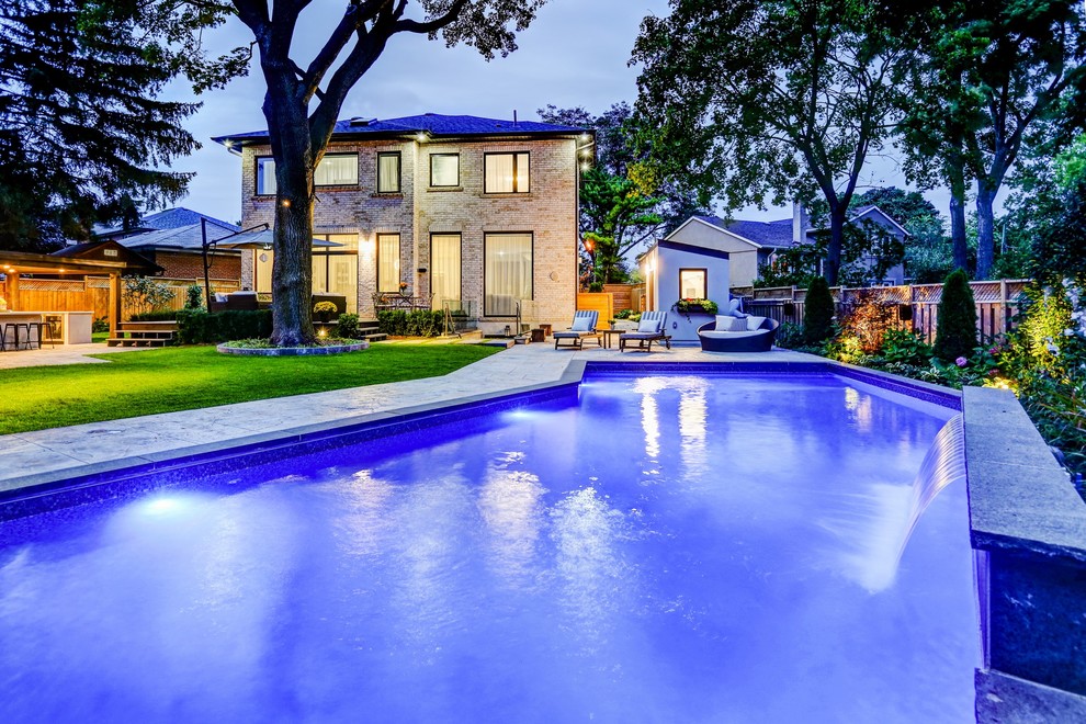 Inspiration for a mid-sized transitional backyard stamped concrete and rectangular pool house remodel in Toronto