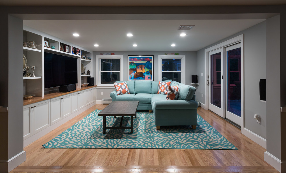 Mid-sized beach style enclosed family room in Boston with grey walls, light hardwood floors, a built-in media wall and brown floor.
