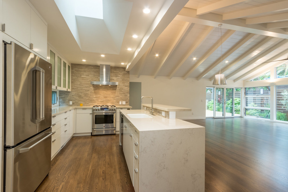 Transitional vaulted ceiling kitchen photo in San Francisco with white cabinets, marble countertops and an island