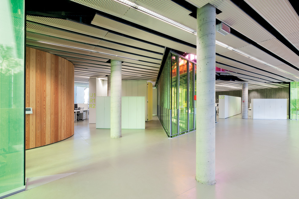 Geräumiges Modernes Arbeitszimmer mit Arbeitsplatz, bunten Wänden, Betonboden, freistehendem Schreibtisch, grauem Boden, eingelassener Decke und vertäfelten Wänden in Mailand