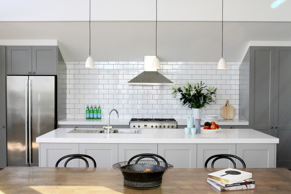 Inspiration for a mid-sized transitional eat-in kitchen in Melbourne with shaker cabinets, grey cabinets, white splashback, subway tile splashback, stainless steel appliances, with island, a drop-in sink and white benchtop.