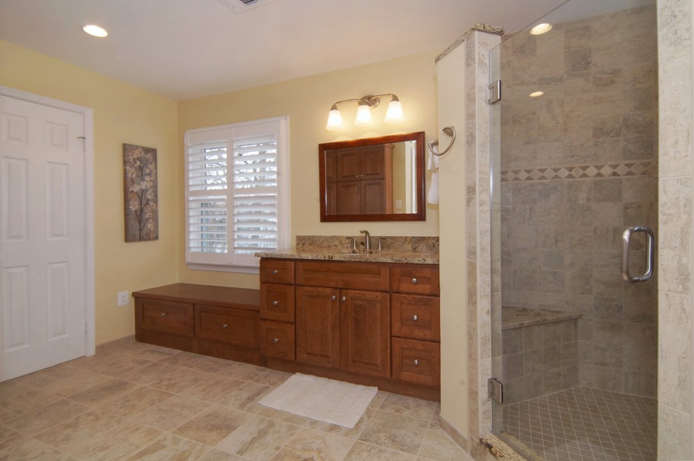 Photo of a large traditional master bathroom in DC Metro with an undermount sink, raised-panel cabinets, medium wood cabinets, granite benchtops, a corner shower, a two-piece toilet, beige tile, ceramic tile and beige walls.