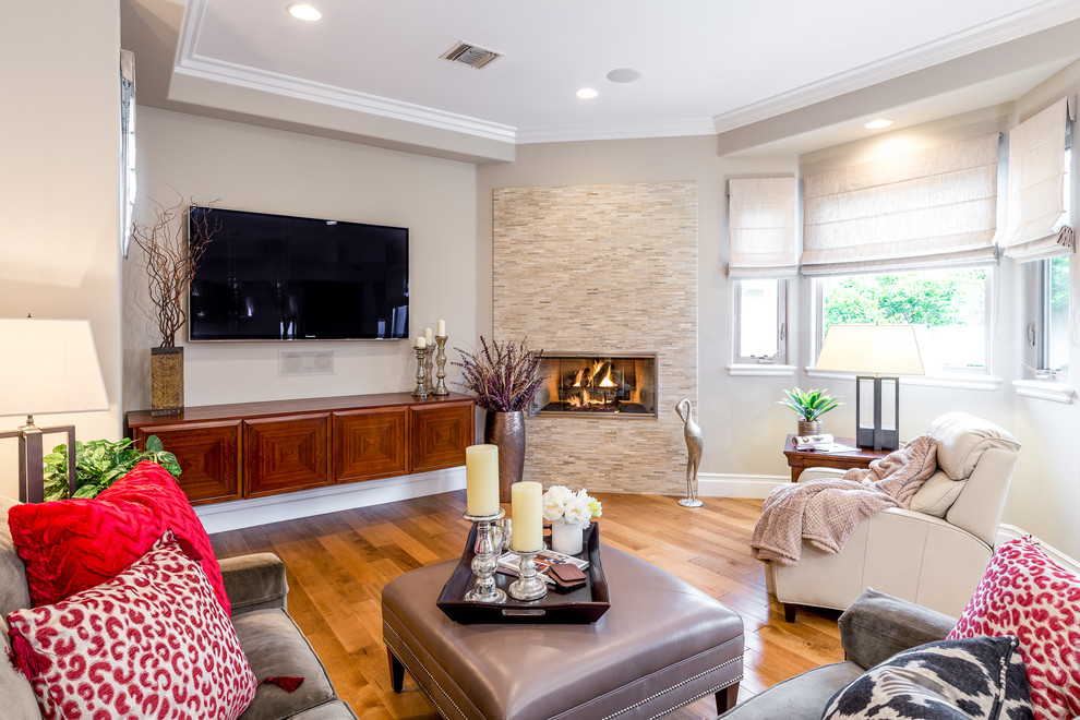 Mid-sized transitional open concept family room in Los Angeles with a wall-mounted tv, beige walls, medium hardwood floors, a hanging fireplace, a tile fireplace surround and brown floor.