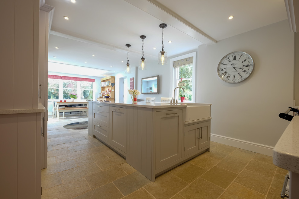 Photo of a large contemporary galley separate kitchen in Hampshire with a farmhouse sink, shaker cabinets, grey cabinets, quartzite benchtops, white splashback, stainless steel appliances, limestone floors, with island, multi-coloured floor and white benchtop.