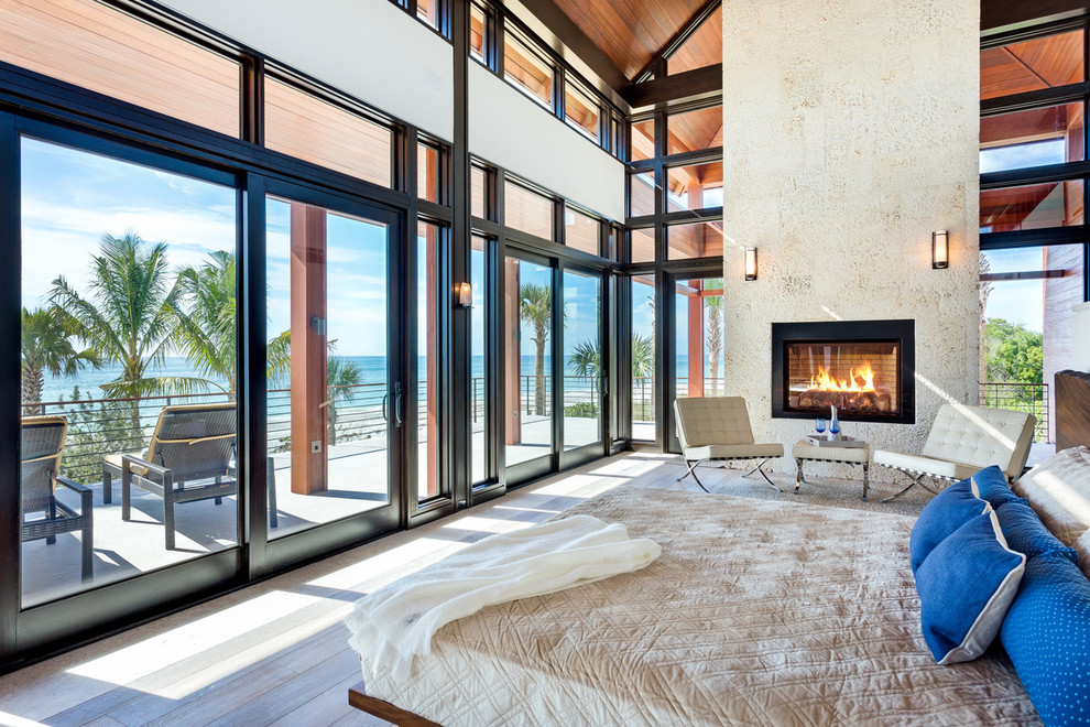 Inspiration for a tropical bedroom in Tampa with a standard fireplace.