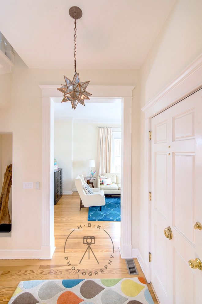 Example of a mid-sized light wood floor and yellow floor entry hall design with white walls