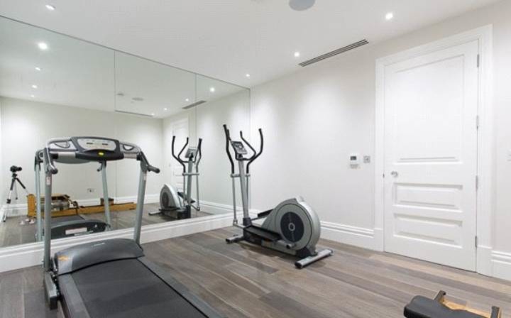 Design ideas for a mid-sized multipurpose gym in London with white walls and medium hardwood floors.