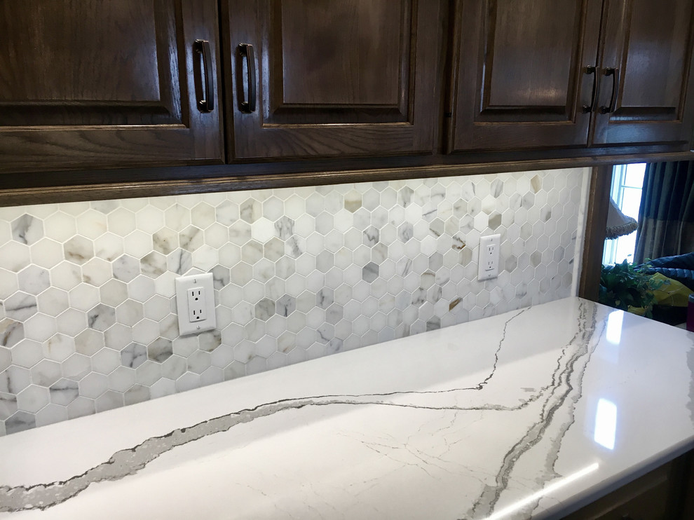 Example of a large transitional u-shaped medium tone wood floor open concept kitchen design with an undermount sink, raised-panel cabinets, medium tone wood cabinets, quartz countertops, multicolored backsplash, mosaic tile backsplash, stainless steel appliances and an island