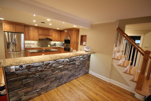 Example of a mid-sized mountain style l-shaped brown floor and light wood floor kitchen design with mosaic tile backsplash, stainless steel appliances, an island, raised-panel cabinets, light wood cabinets, granite countertops and multicolored backsplash