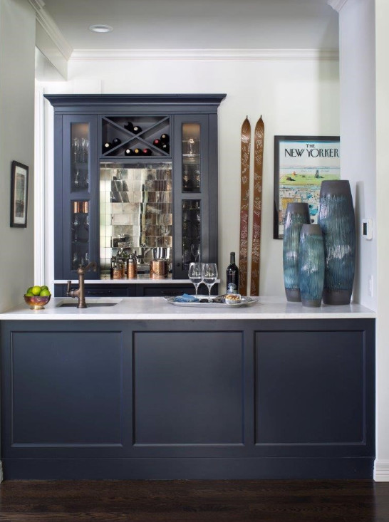 Inspiration for a mid-sized transitional galley wet bar in Denver with an undermount sink, glass-front cabinets, blue cabinets, marble benchtops, dark hardwood floors, brown floor and white benchtop.