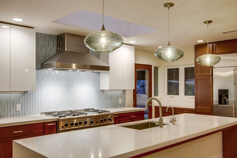 Photo of a large midcentury l-shaped separate kitchen in San Diego with a single-bowl sink, recessed-panel cabinets, medium wood cabinets, quartz benchtops, blue splashback, glass tile splashback, stainless steel appliances, light hardwood floors, with island, beige floor and white benchtop.