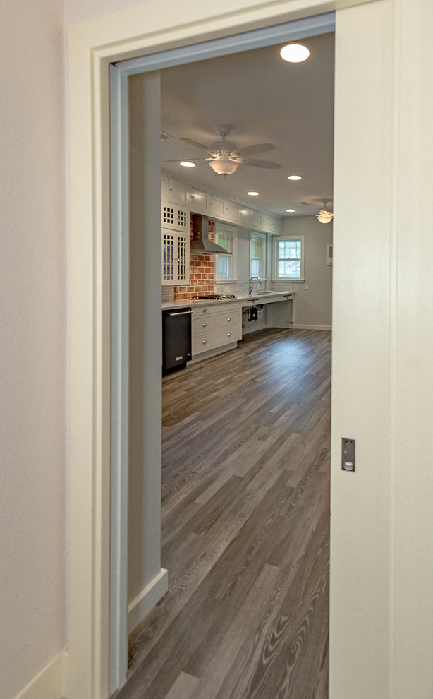 Large mountain style galley dark wood floor eat-in kitchen photo in Austin with a farmhouse sink, open cabinets, white cabinets, quartzite countertops, multicolored backsplash, marble backsplash, stainless steel appliances and no island