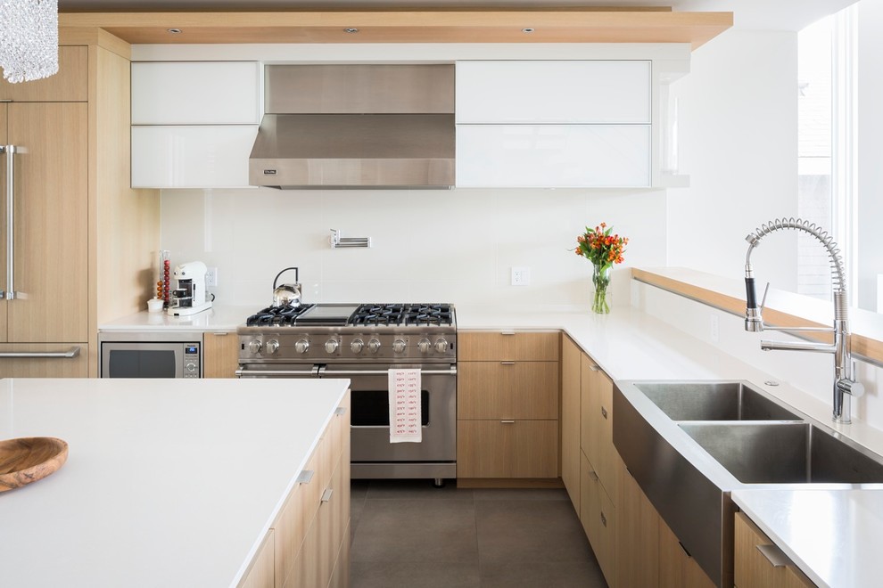 Inspiration for a mid-sized contemporary l-shaped open plan kitchen in Vancouver with a double-bowl sink, flat-panel cabinets, light wood cabinets, stainless steel appliances, glass sheet splashback, white splashback and with island.
