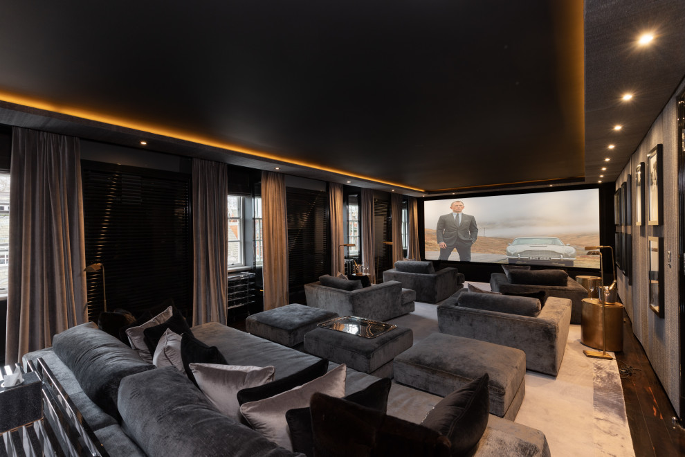 Example of a large trendy enclosed dark wood floor and black floor home theater design in London with black walls and a projector screen