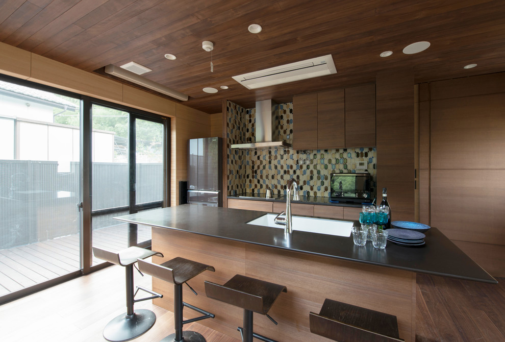 Asian galley kitchen in Other with a drop-in sink, flat-panel cabinets, brown cabinets, medium hardwood floors, with island, brown floor and brown benchtop.
