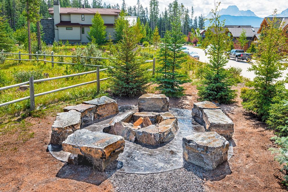 This is an example of a mid-sized country backyard patio in Calgary with a fire feature and natural stone pavers.