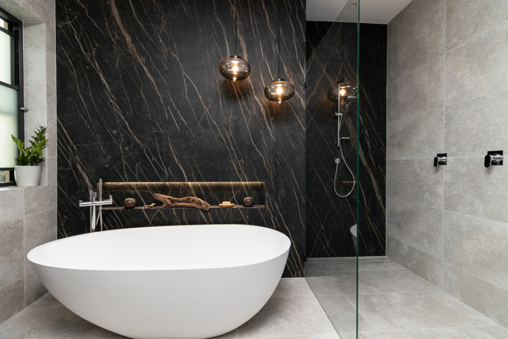 Expansive modern 3/4 bathroom in Sydney with flat-panel cabinets, dark wood cabinets, a freestanding tub, an open shower, a wall-mount toilet, gray tile, porcelain tile, multi-coloured walls, porcelain floors, an undermount sink, tile benchtops, grey floor, an open shower and white benchtops.